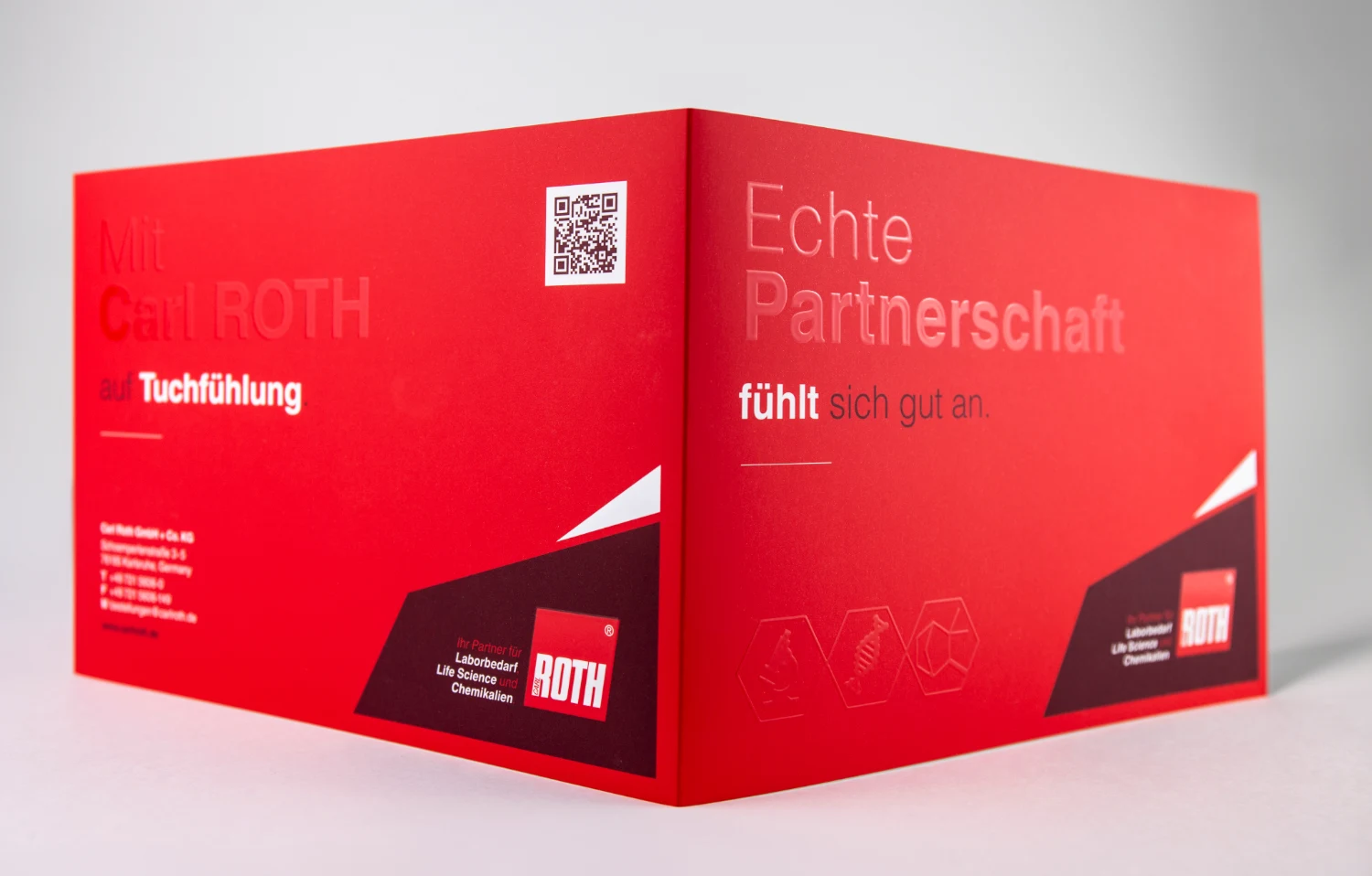 Aufgestellter roter Carl-Roth-Umschlag mit sichtbarer Falzkante und bedruckten Seiten