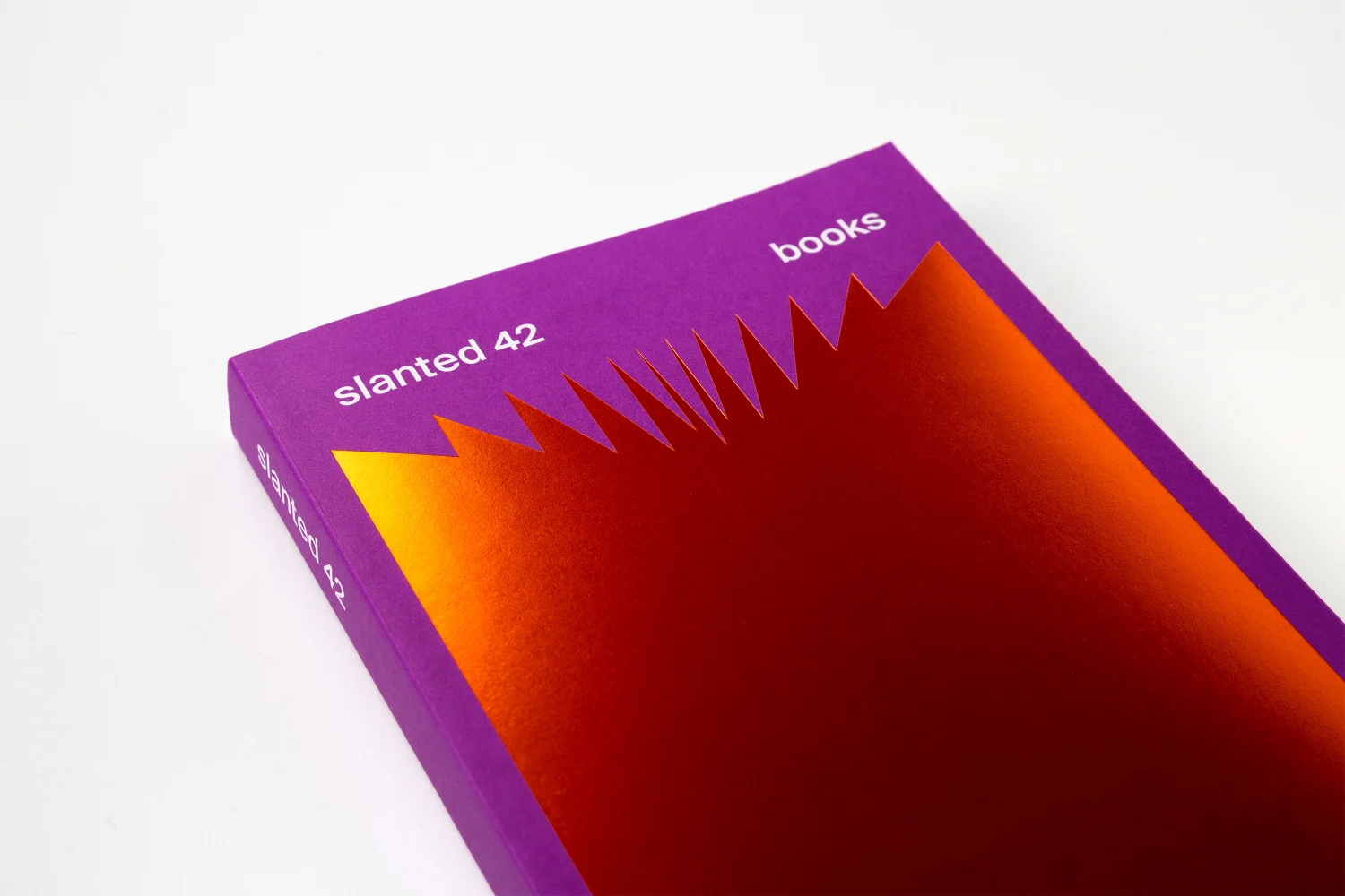 Slanted 42 - Books mit sichtbarem Buchrücken und orangefarbener Heißfolienprägung auf violettem Umschlag