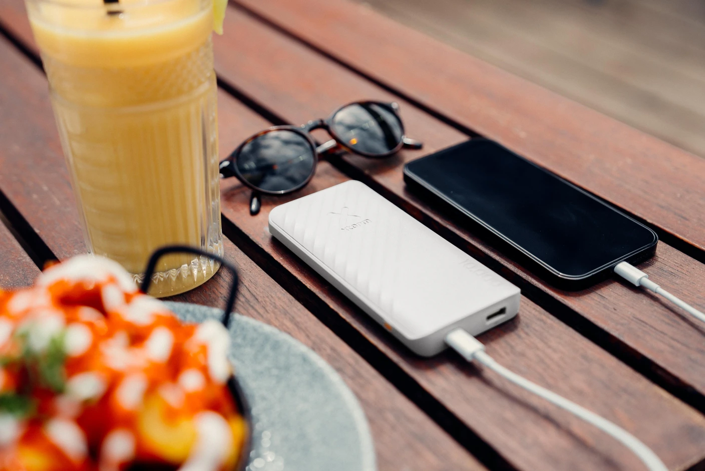 Weiße Powerbank lädt ein Smartphone auf einem Holztisch