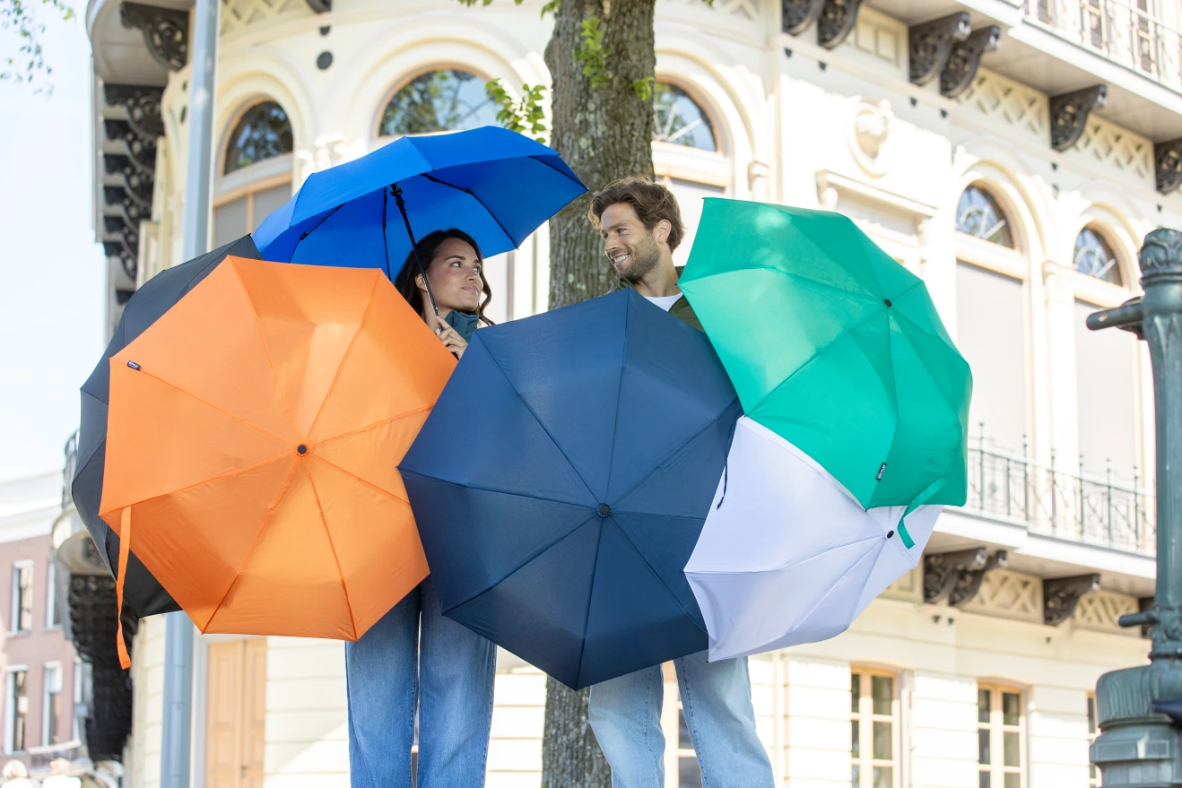 Zwei Personen mit aufgespannten Regenschirmen in verschiedenen Farben