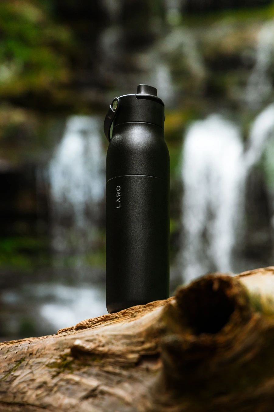Schwarze Trinkflasche vor einem Wasserfall